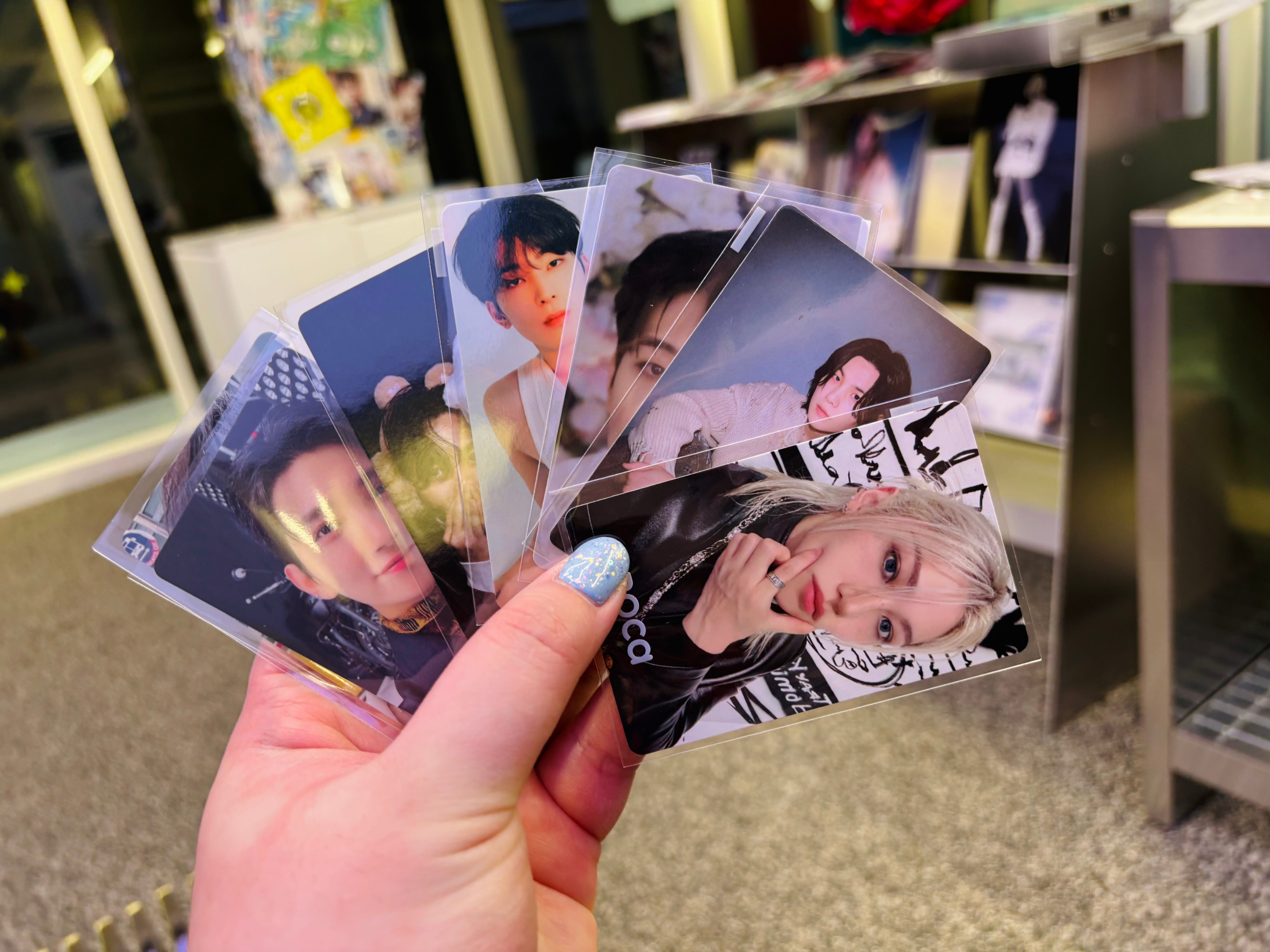 A shot of K-pop photocards fanned out in a person's hand.