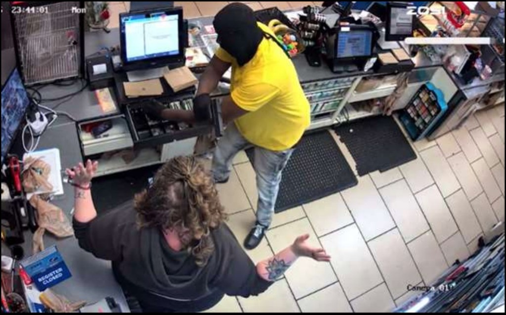 Surveillance footage showing Justin Farley, in a black ski mask and yellow shirt, reaching into a cash register while a person with curly hair and a black hoodie stands with arms raised.