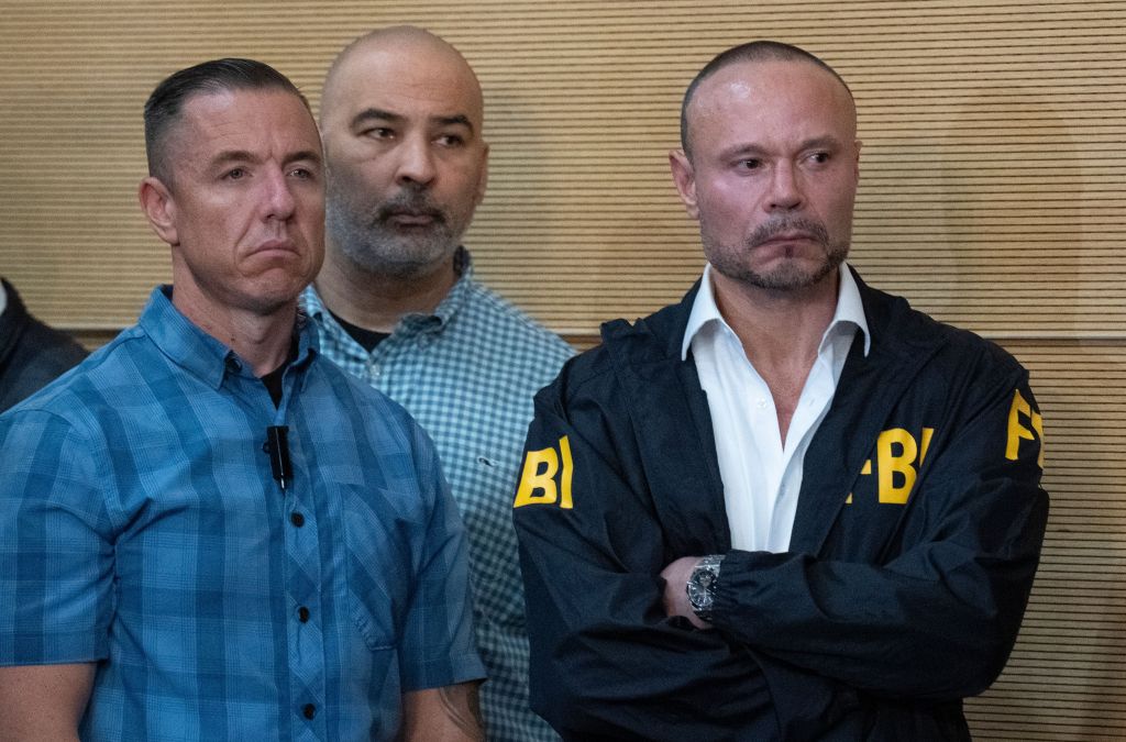 FBI Deputy Director Dan Bongino (right) stands at a news conference with two other men.