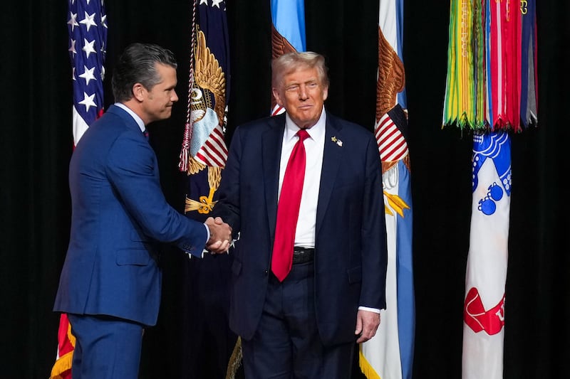 US Secretary of Defense Pete Hegseth shakes hands with US President Donald Trump as Trump takes the stage to address senior military officers