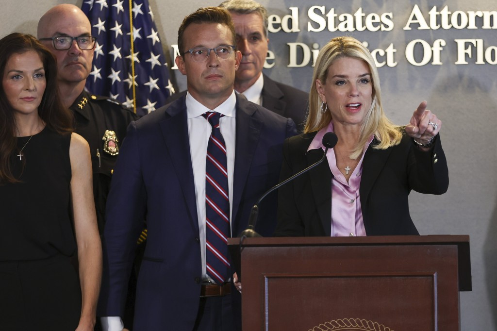 U.S. Attorney General Pam Bondi speaking at a news conference, with other individuals behind her.