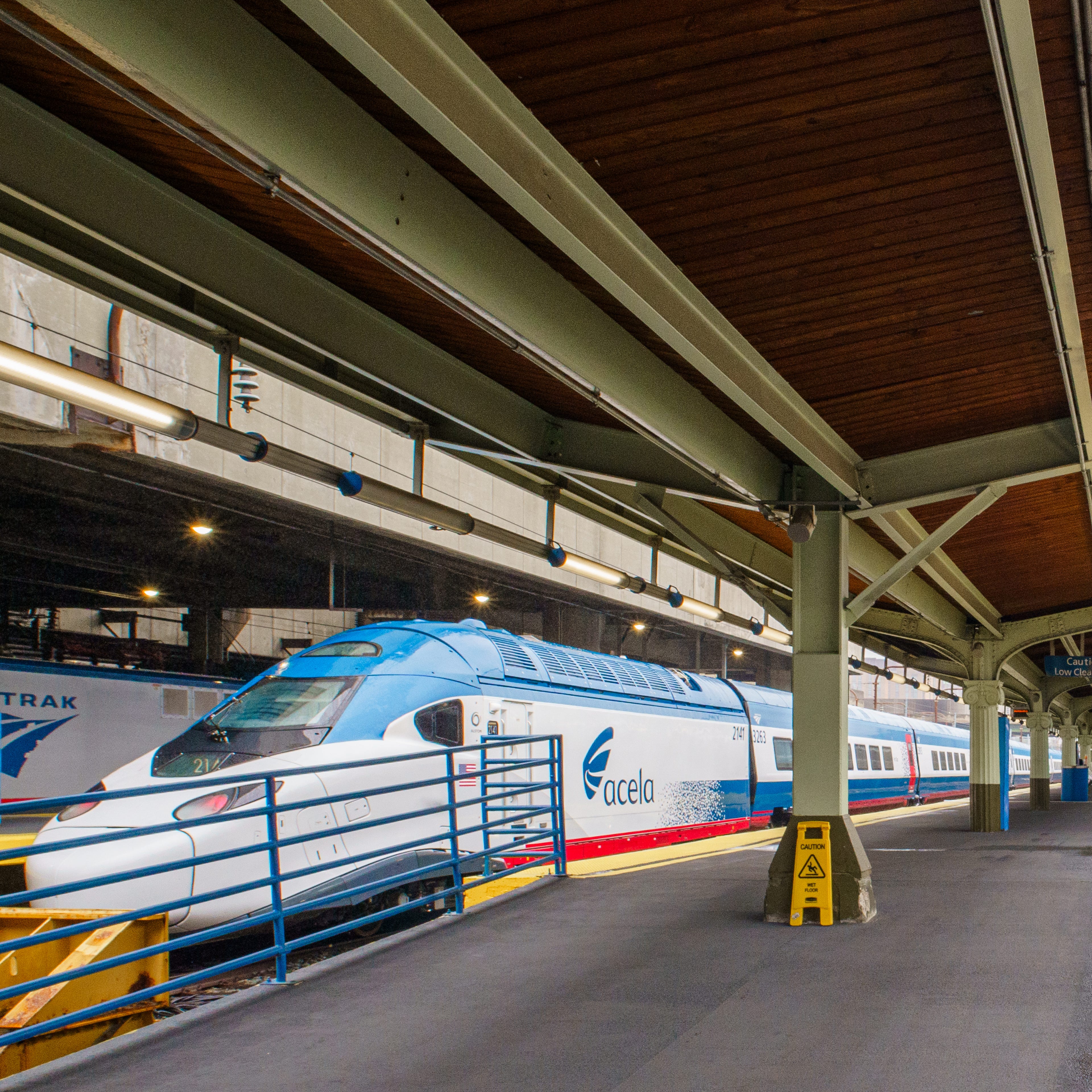 An Amtrak NextGen Acela train stopped at a covered platform