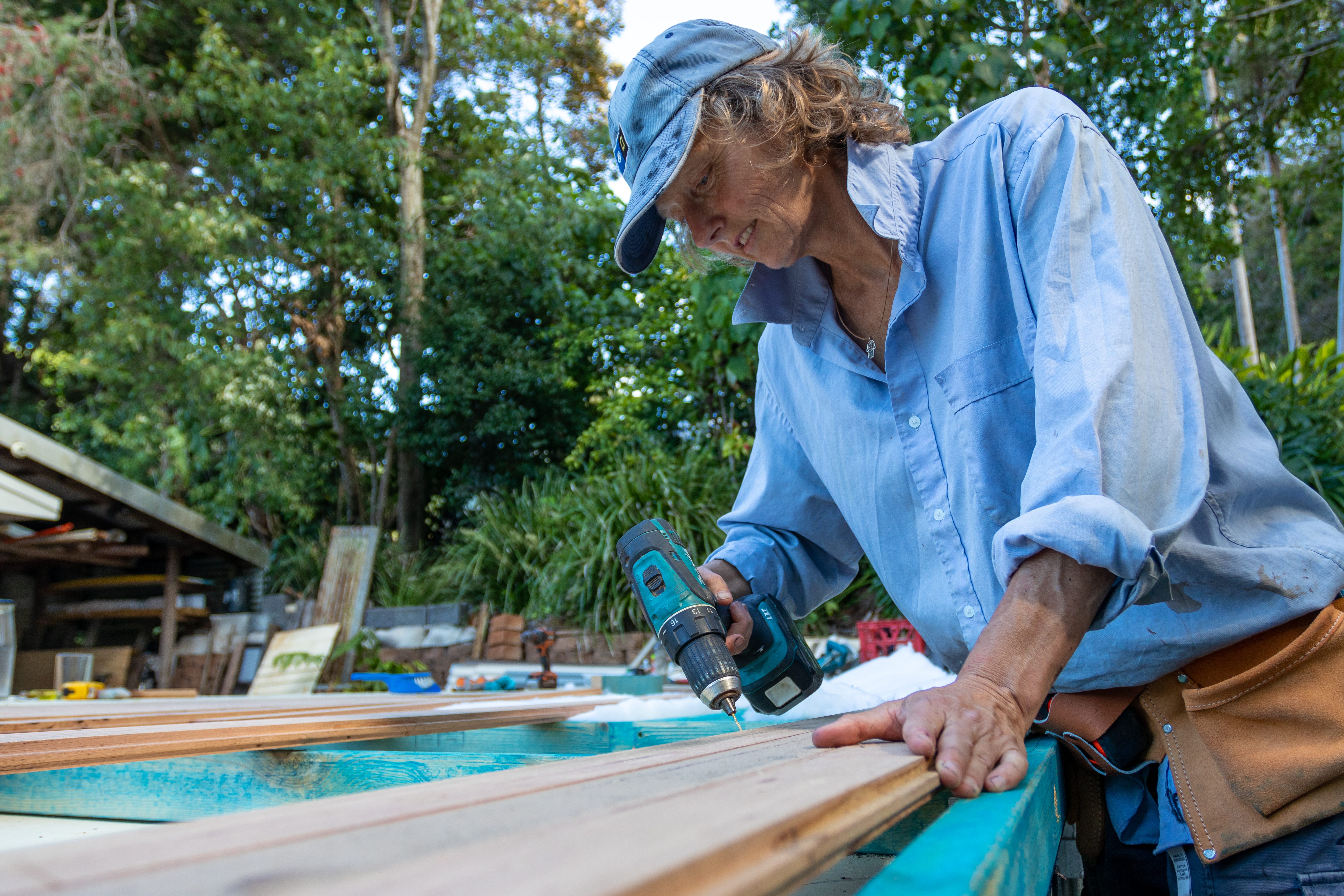 author using screwdriver on wood while building tiny house