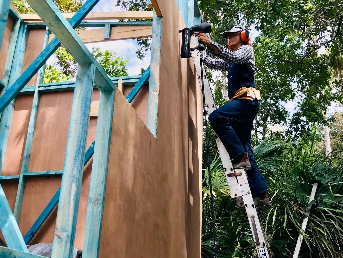 Louise Southerden on a ladder building her tiny house