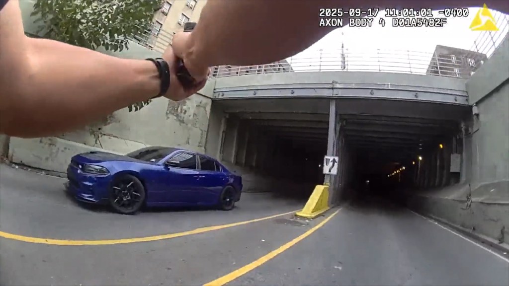 Body camera footage of a police officer aiming a weapon at a stolen blue car with flat tires in the South Bronx.