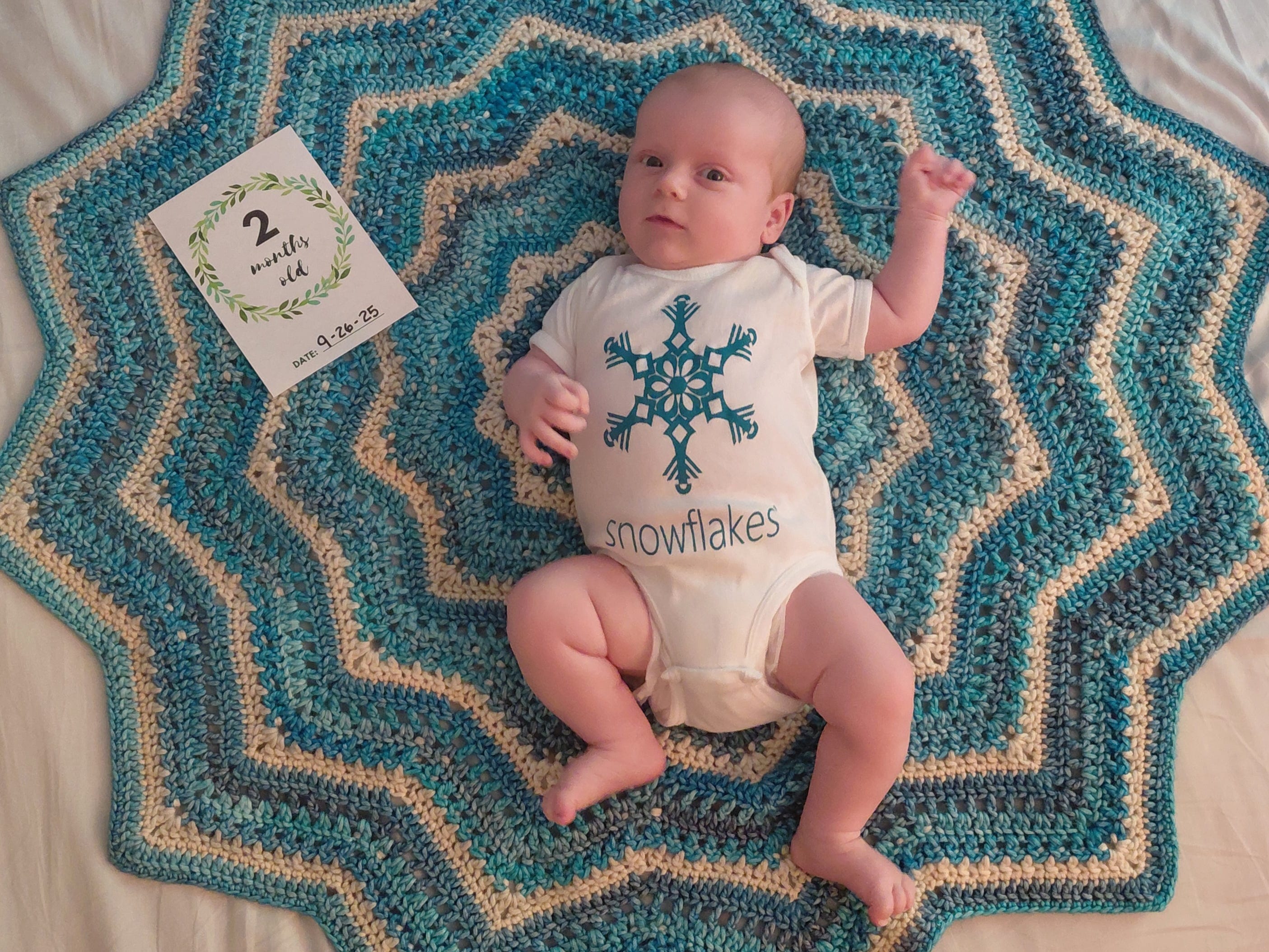 A baby lying on a mat with a card stating
