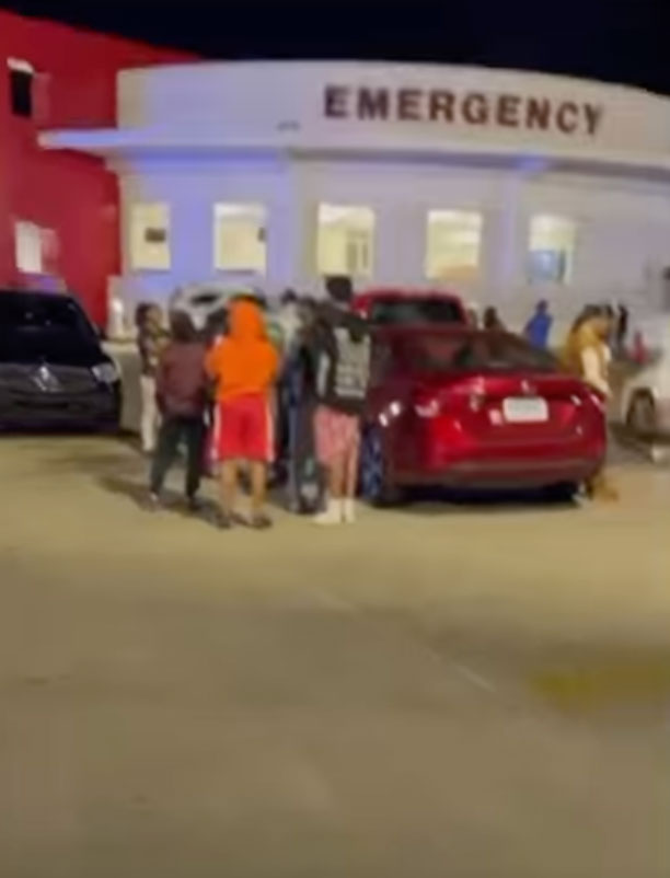 People gathered outside an emergency room building at night.