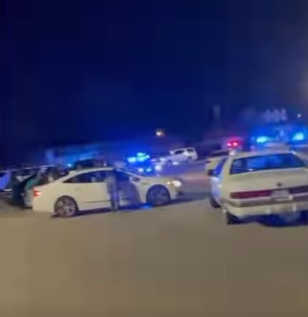 Police cars with flashing blue lights at night.