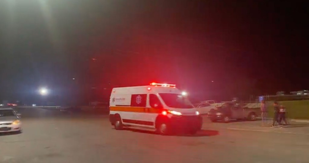 An ambulance with flashing red lights at night.