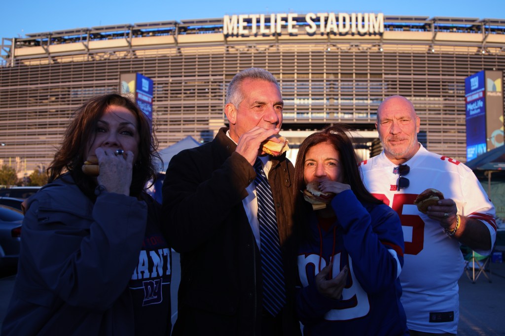 Republican candidate for governor of New Jersey Jack Ciattarelli eating a sandwich outside MetLife Stadium with three other people.