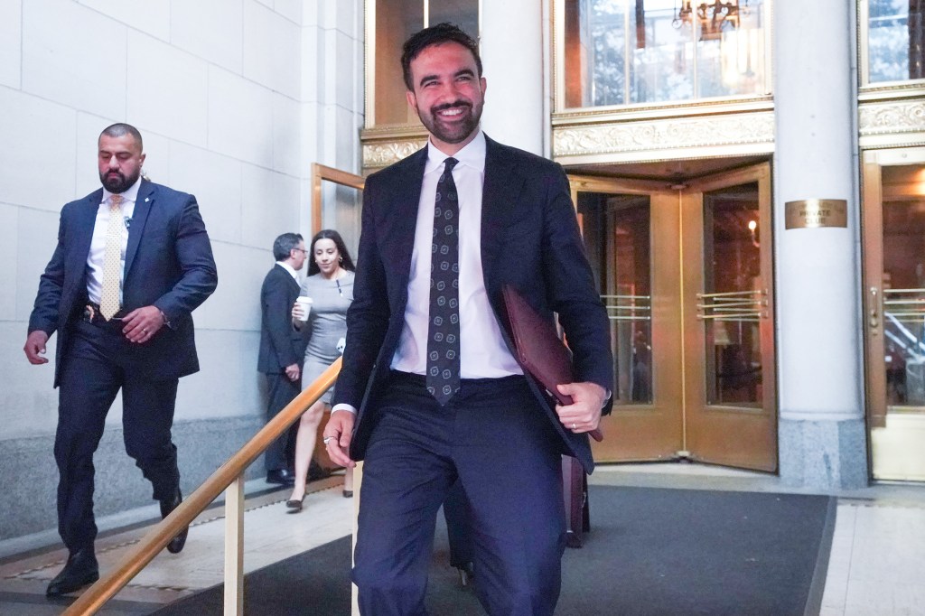 mamdani in a suit smiling outside the ny athletic club 