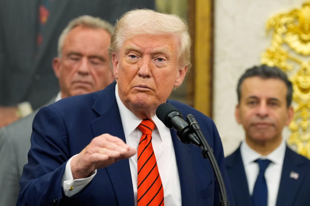 President Donald Trump speaking in the Oval Office with Health and Human Services Secretary Robert F. Kennedy Jr. and FDA Commissioner Dr. Marty Makary listening in the background.