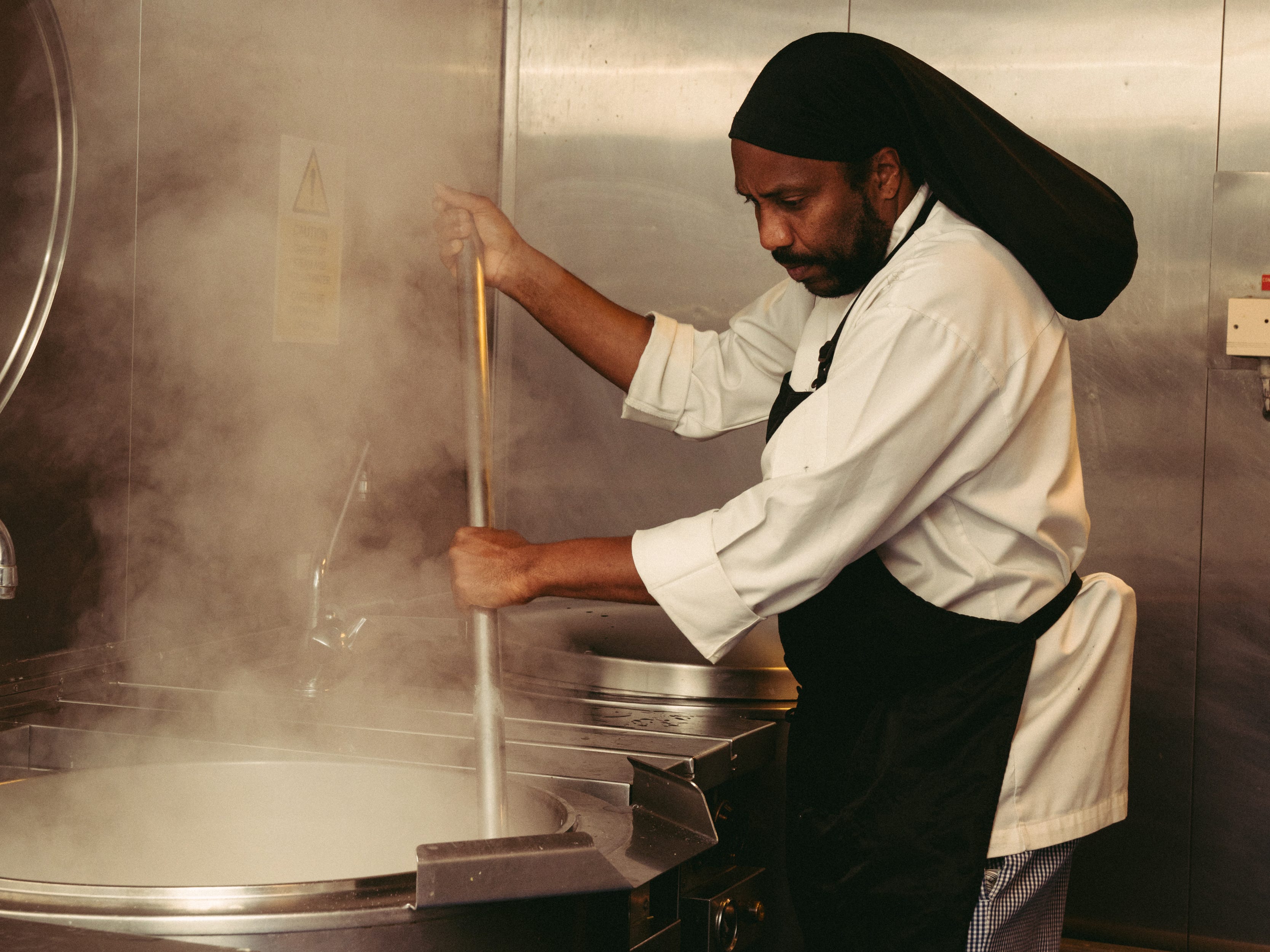A cook on the Prince of Wales stirs a giant pot in the galley.