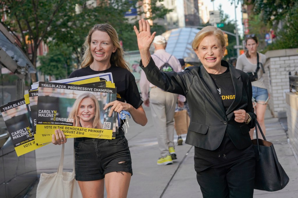 Carolyn Maloney waving while a woman next to her holds campaign posters.
