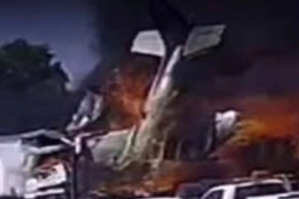 The wreckage of a plane engulfed in flames and smoke.