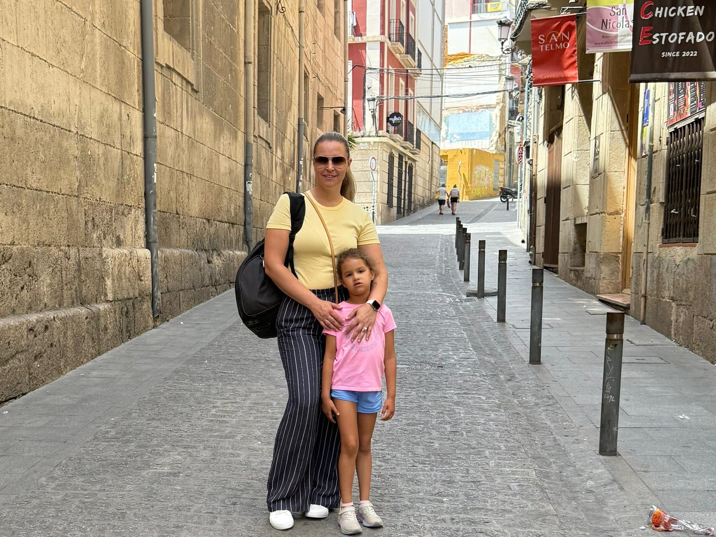 Izabela Oquendo and her young daughter stand in the middle of a Spanish street.