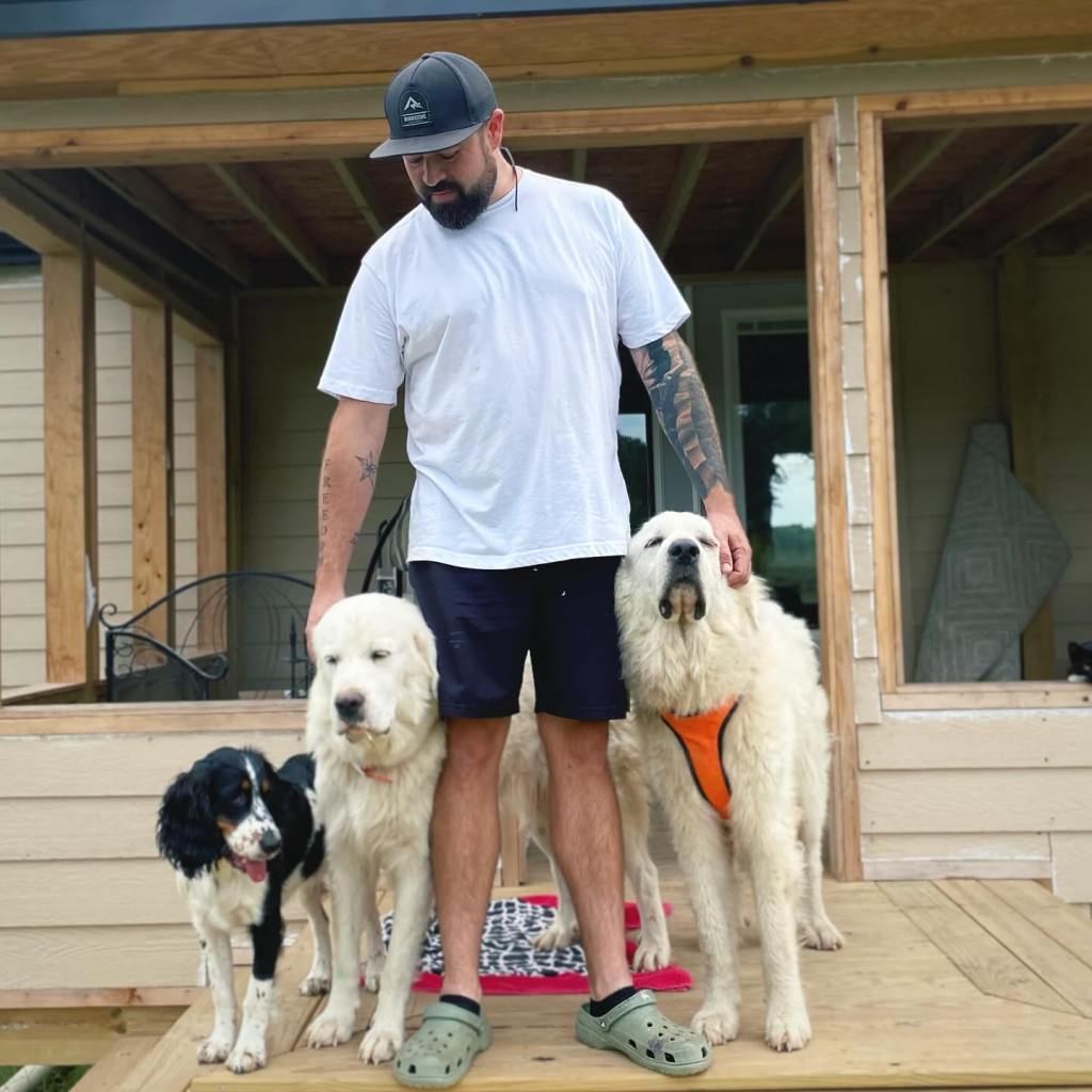 A man with three dogs on a porch.