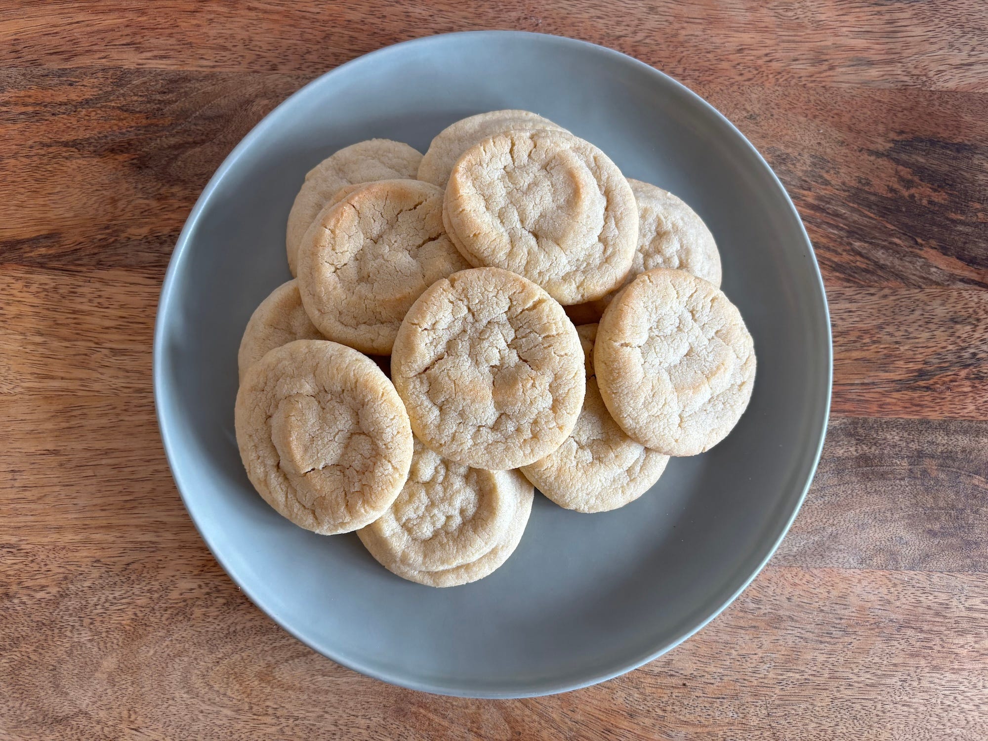 A plate full of sugar cookies on a wooden table.