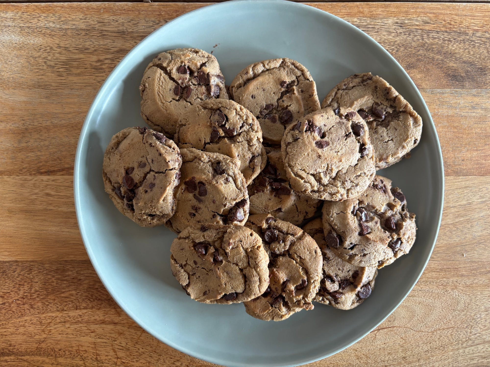 A plate of chocolate chip cookies on a wooden table.