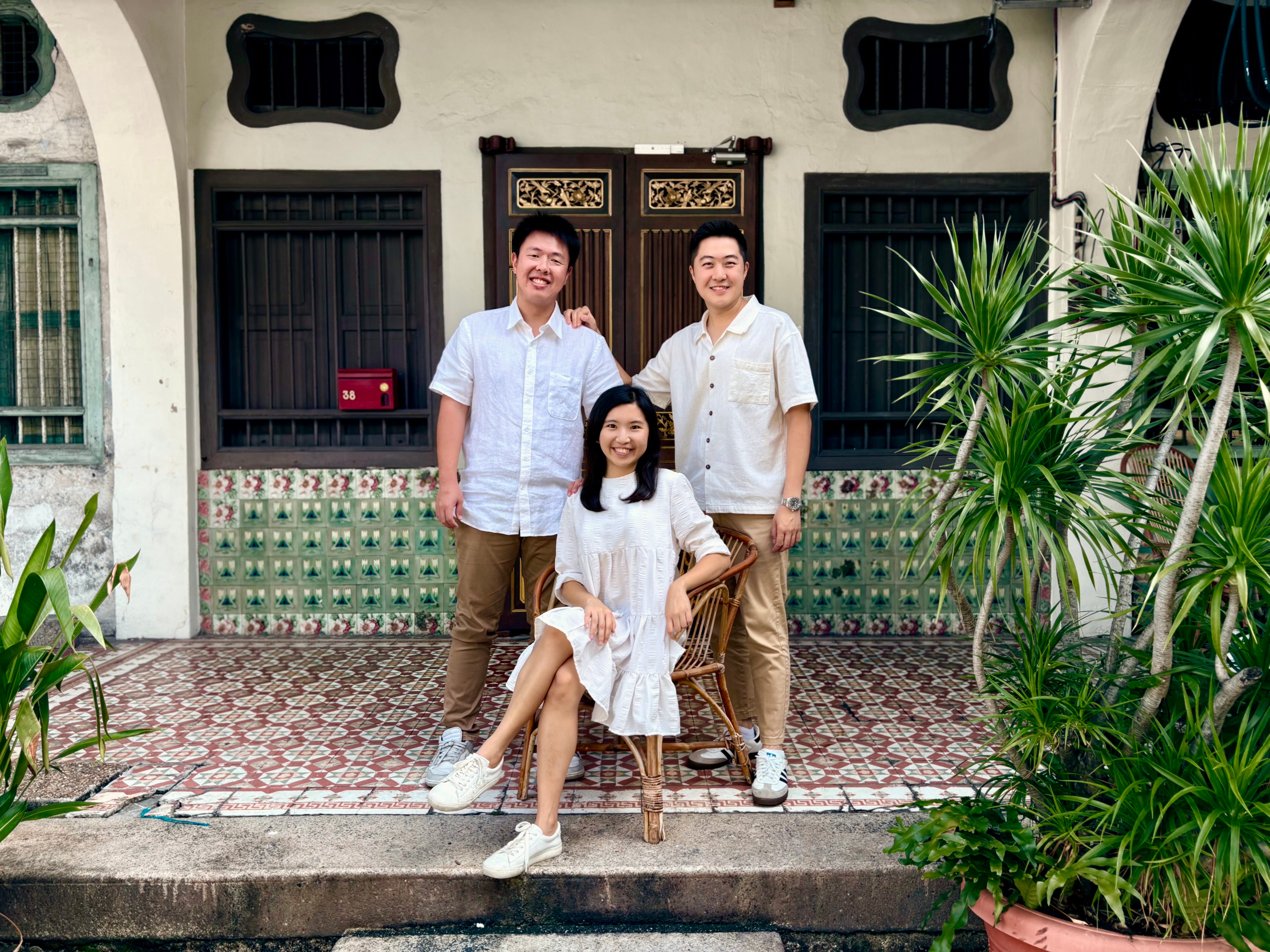 Three people standing in front of a s hophouse in Penang, Malaysia.