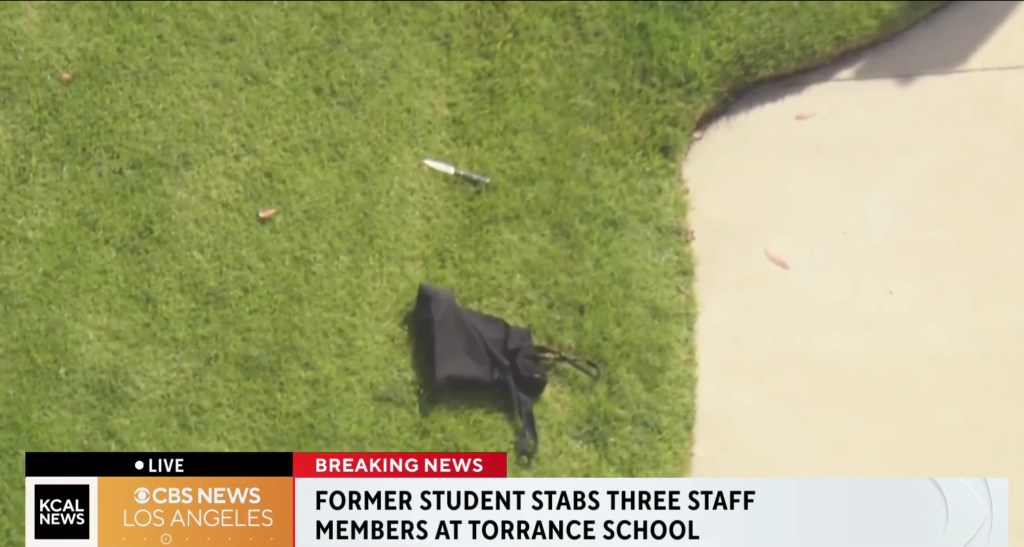 A knife and a black bag laying in the grass next to a sidewalk with news banners at the bottom.