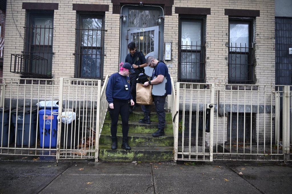 Three crime scene investigators work on the steps outside 207 Troy Avenue in Crown Heights, Brooklyn.