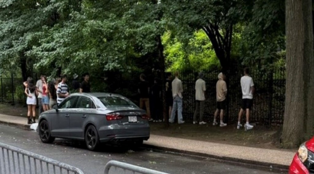 A row of young men urinating on the street.
