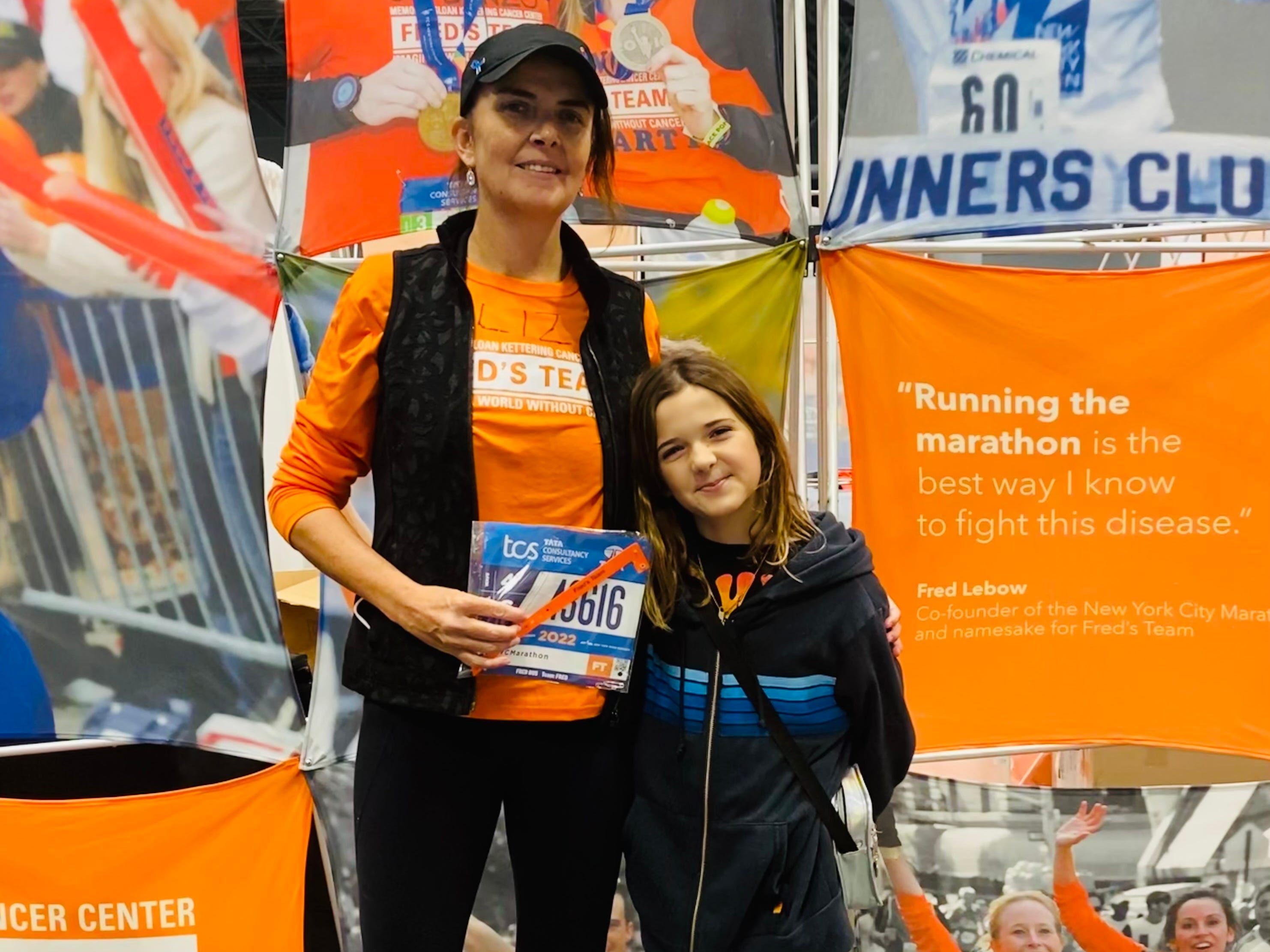 A woman with her daughter standing in front of marathon posters