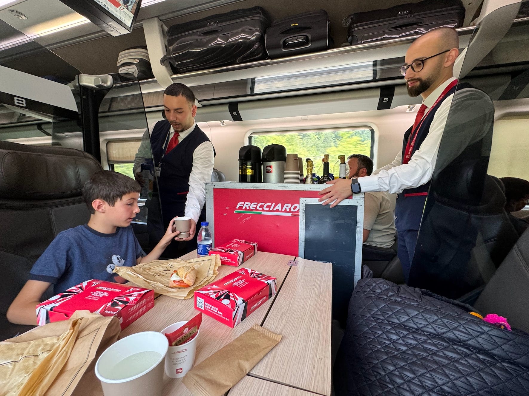Train attendants serving drinks in a first-class train car.