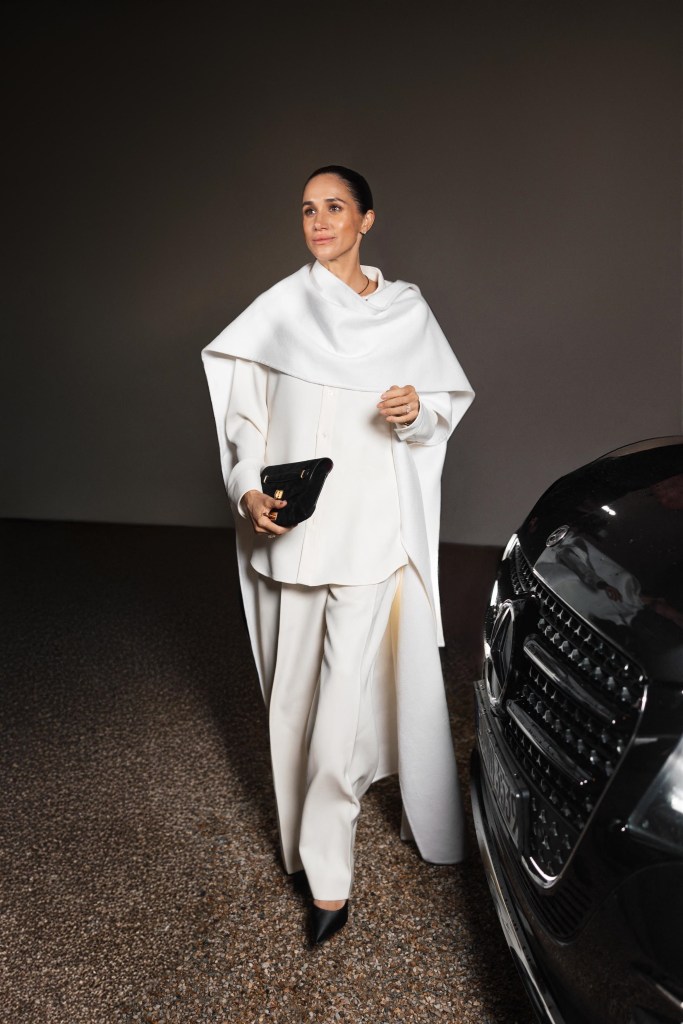 Meghan Markle in a white Balenciaga outfit with a black handbag at Paris Fashion Week.