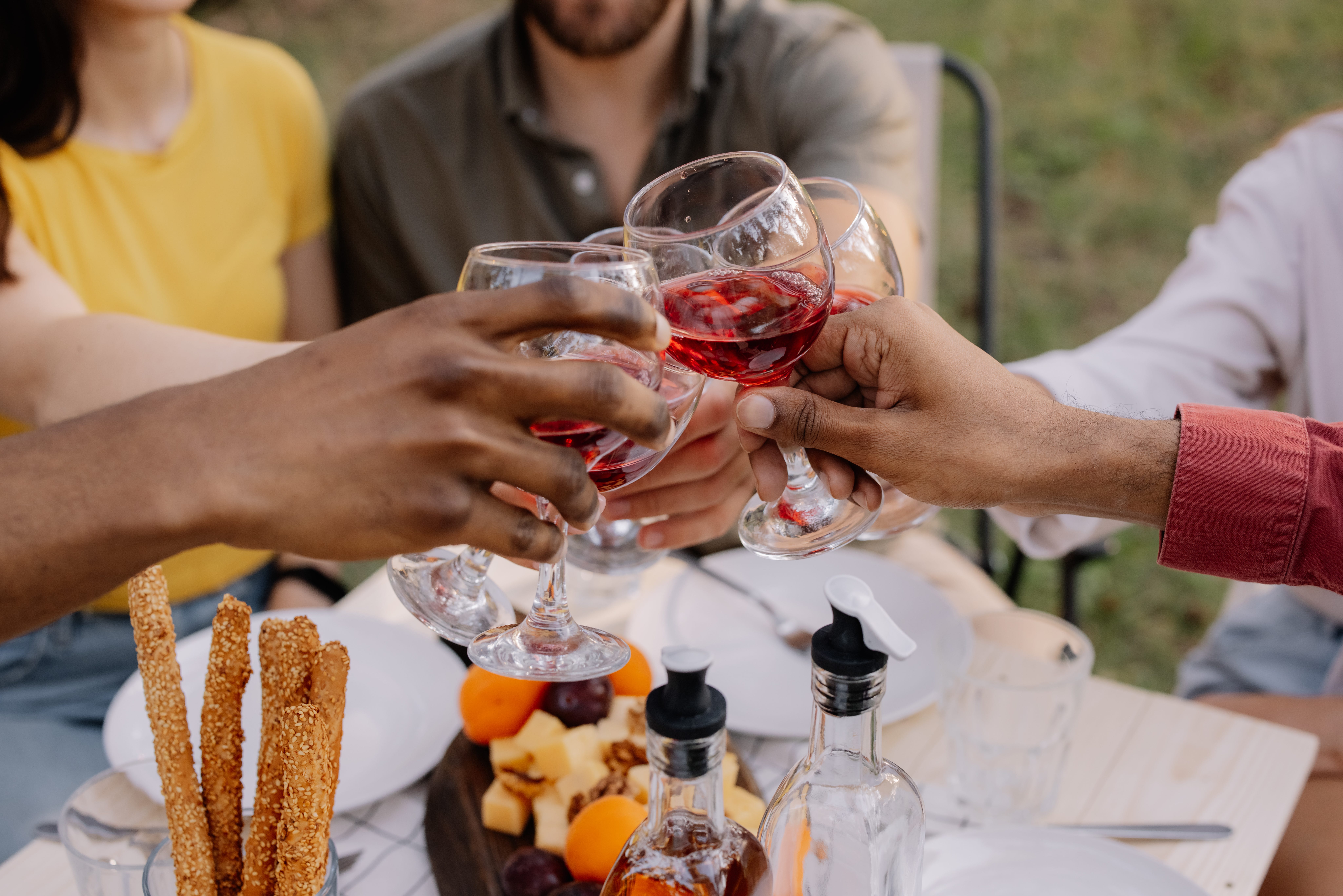 People toasting red wine glasses