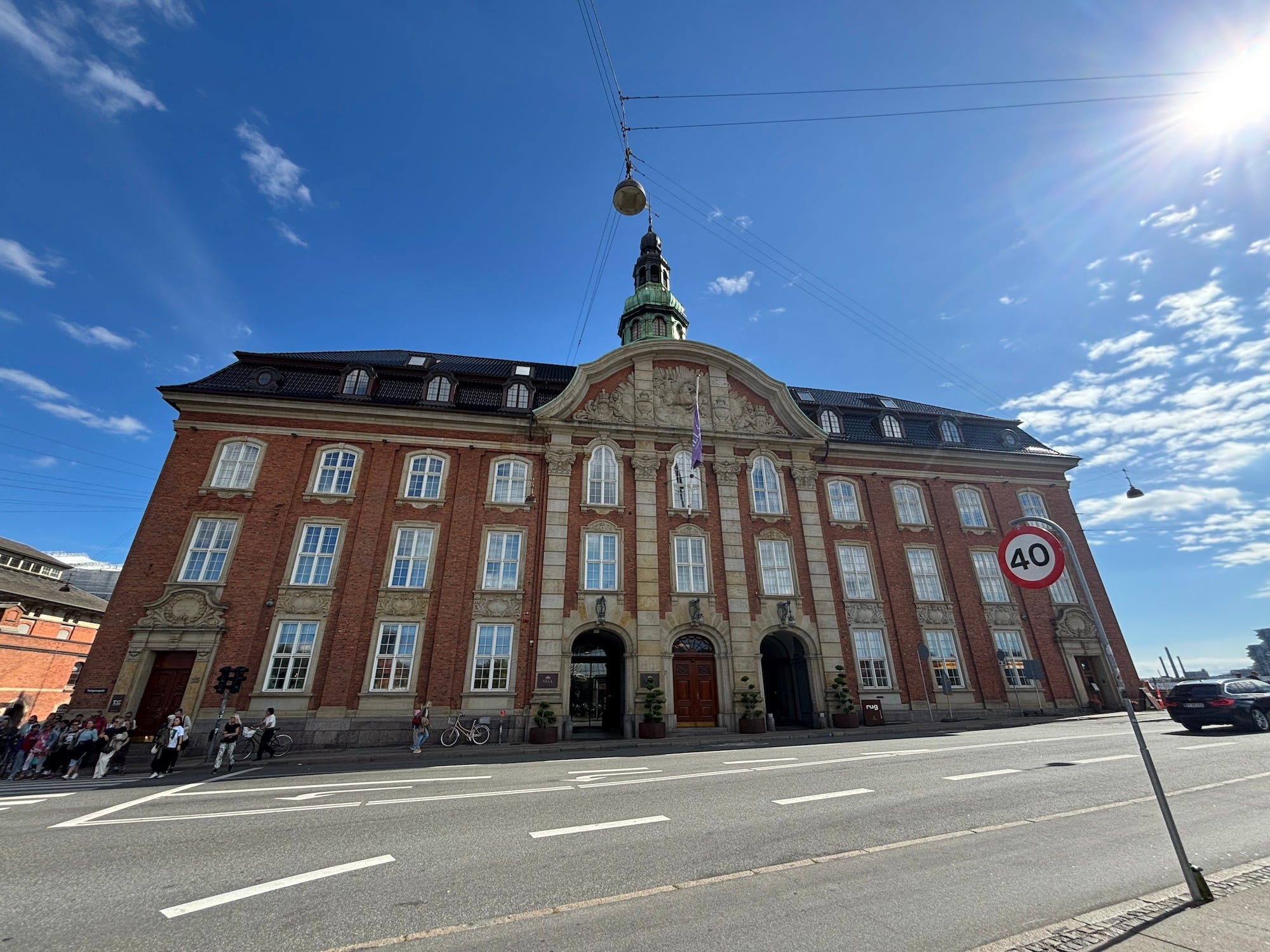 A wide photo of a stately hotel with a brick and stone exterior. A blue sky sits behind it.