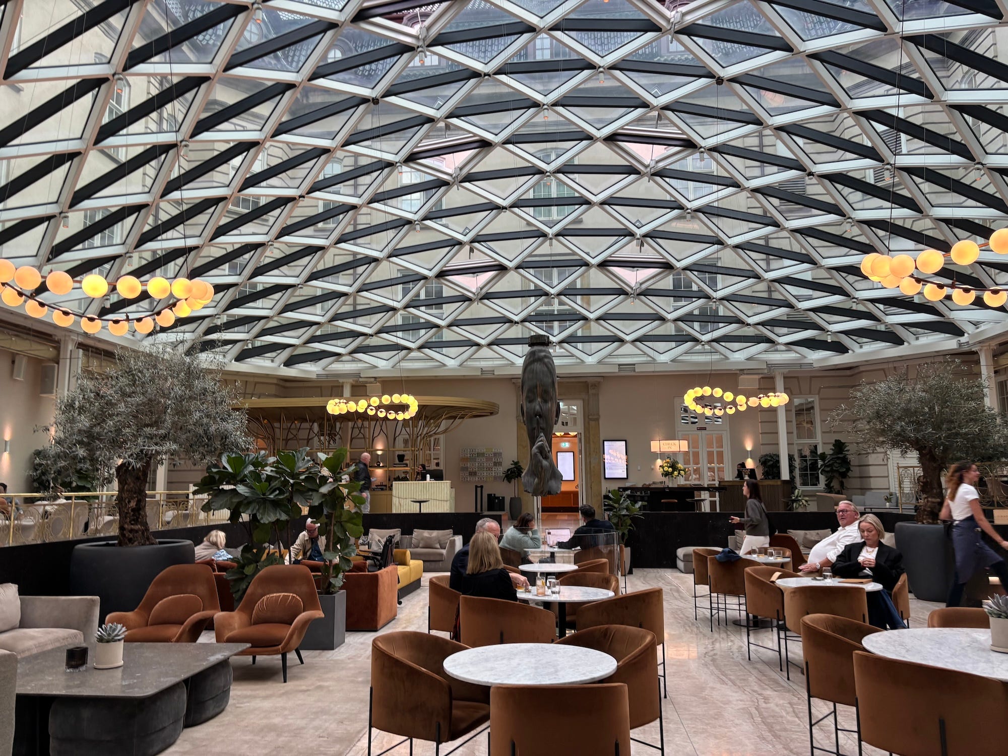 A photo of a lobby of a hotel with a glass ceiling.