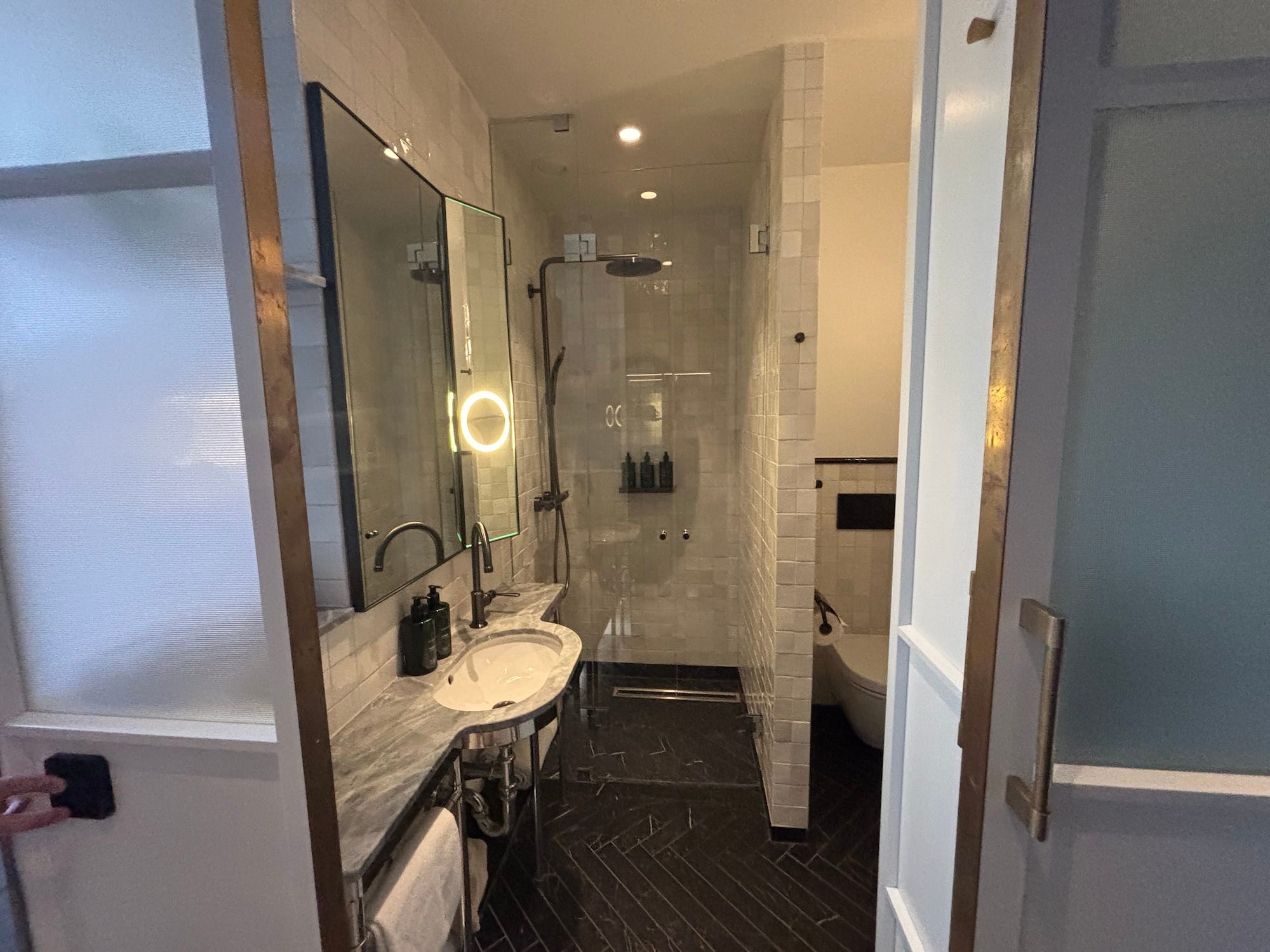 A small bathroom in a hotel. A ring light is built into the mirror.