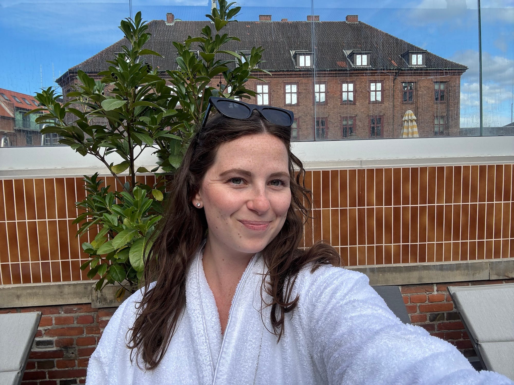 A selfie of a woman in a robe sitting by a pool.