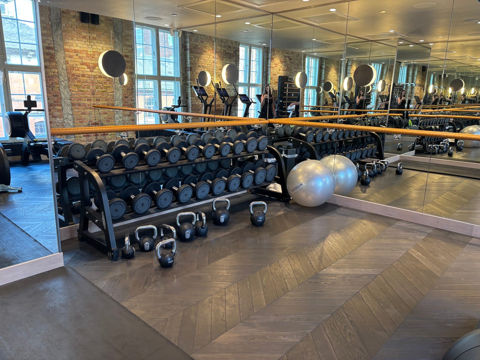 A rack of weights in a small gym with mirrored walls.