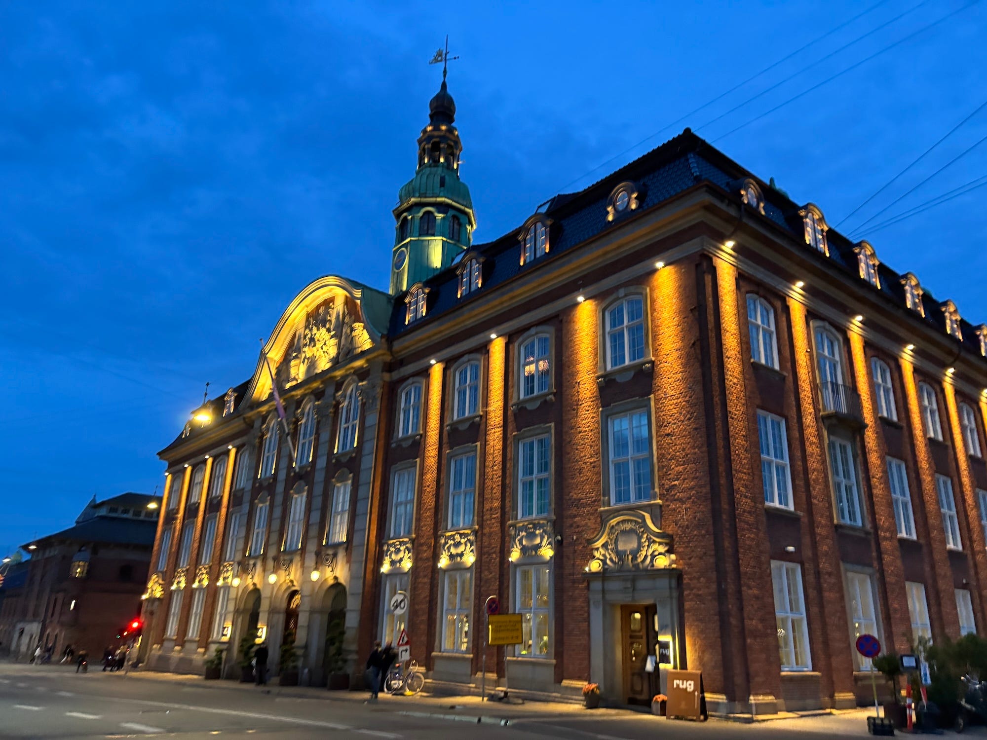 A photo of a large hotel made of brick and stone at night.