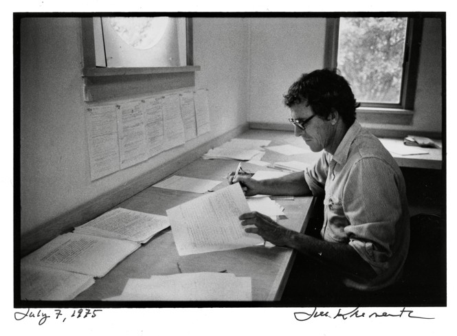 A black and white photograph of Matthiessen at his writing desk
