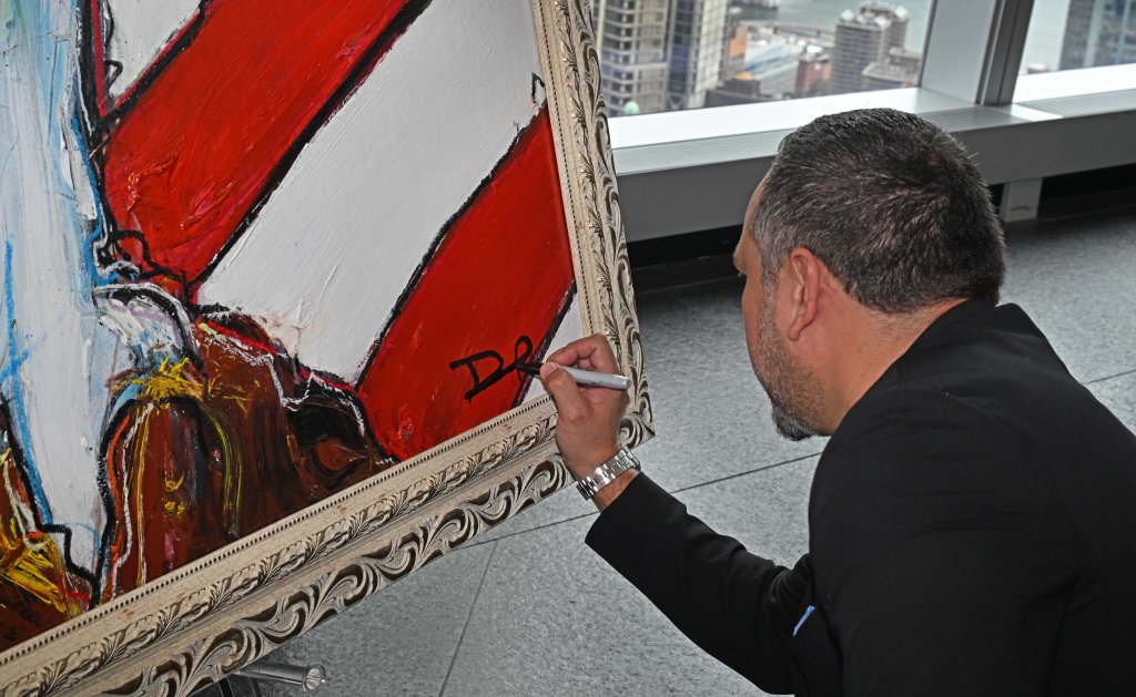 Banegas signs the painting. 