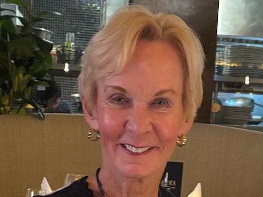 A woman wearing a black and white top and a gold necklace.