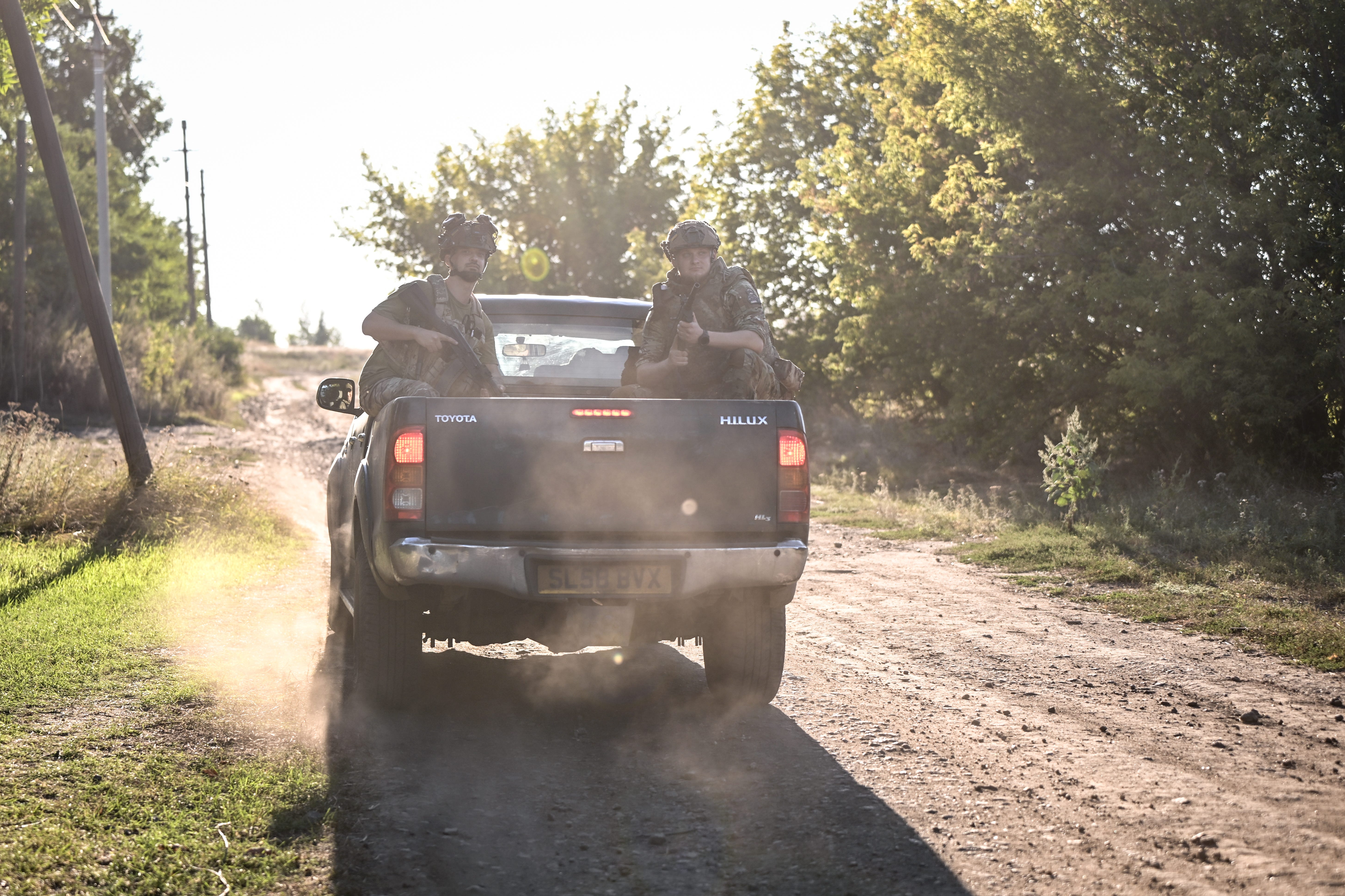 Ukrainian troops sit in the back of a pickup truck.