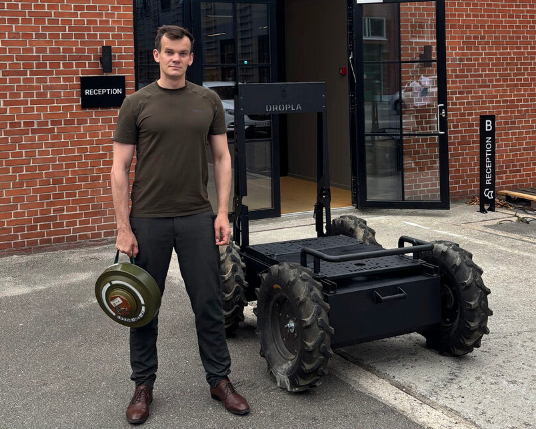 Shvaydak holds an anti-tank landmine next to an uncrewed ground vehicle.
