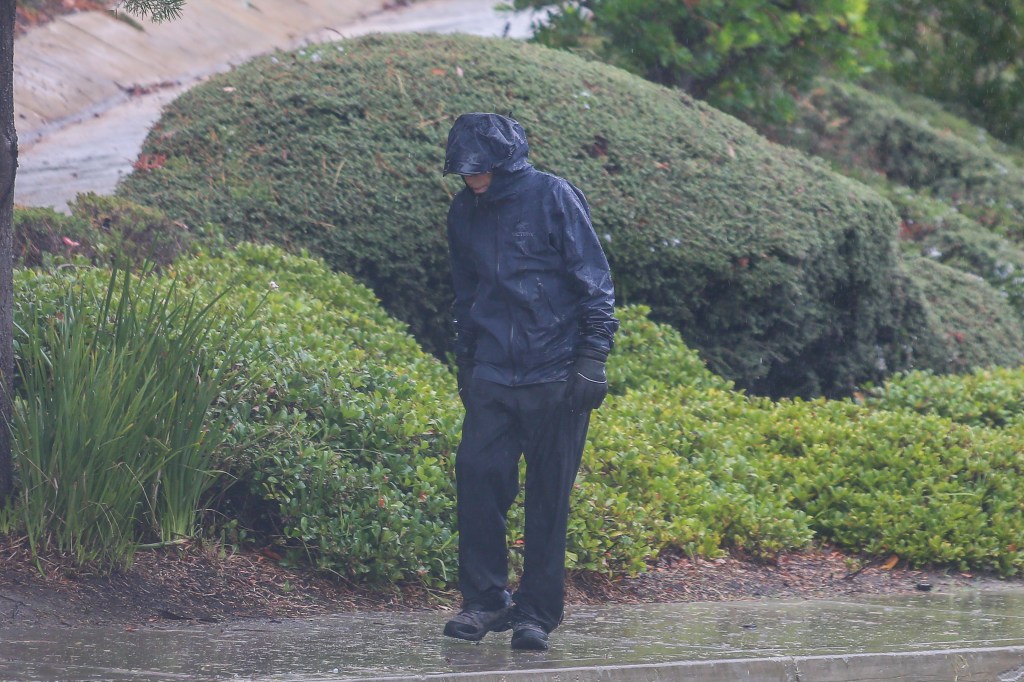 G. Scott Romney walks in the rain near his home in Valencia, California.