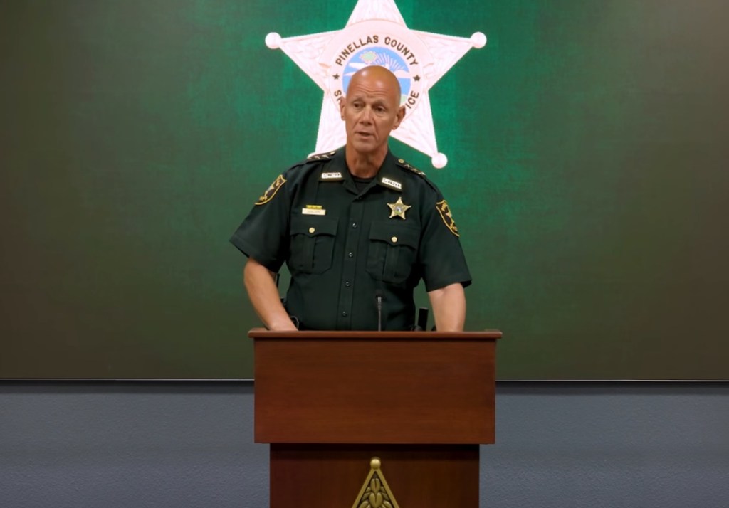 Sheriff Bob Gualtieri speaking at a podium against a green backdrop with the Pinellas County Sheriff's Office star logo.
