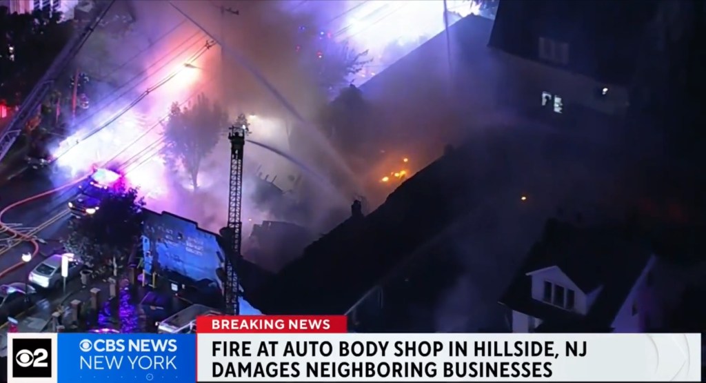 Smoke and flames rise from the auto body shop as firefighters battle the blaze in Hillside, NJ.