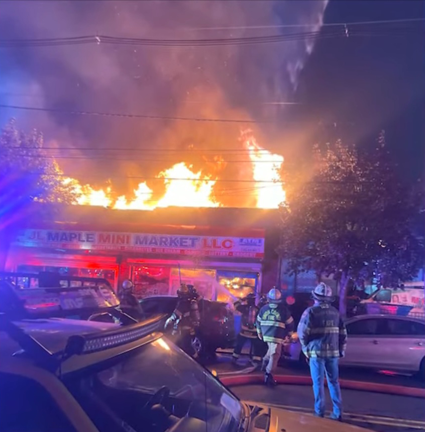 Firefighters battle a blaze at a mini market after it caught fire from explosion from an explosion at a nearby auto shop on Oct. 14, 2025.