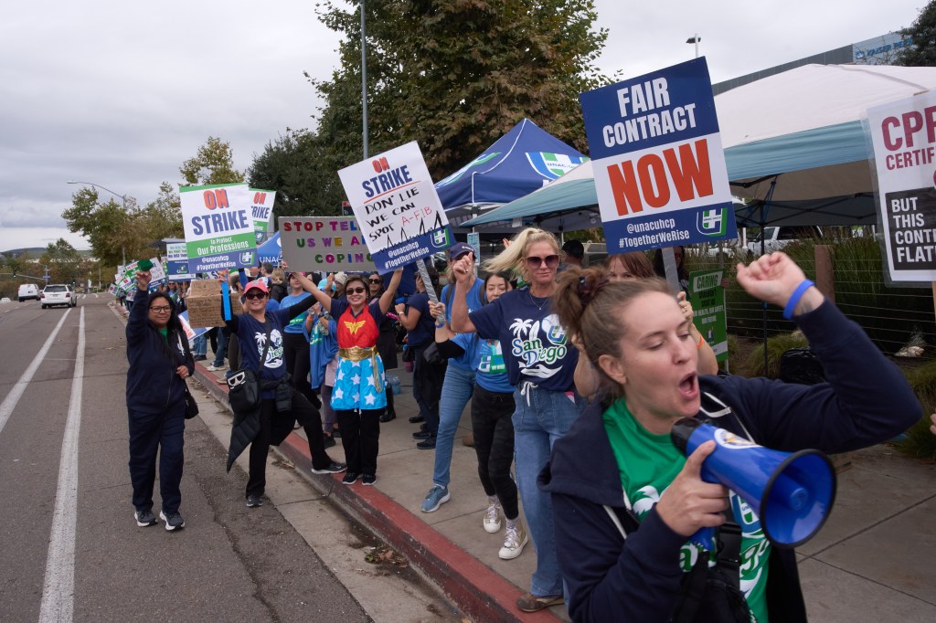 Kaiser Permanente health care workers holding signs and chanting during a strike in San Diego.