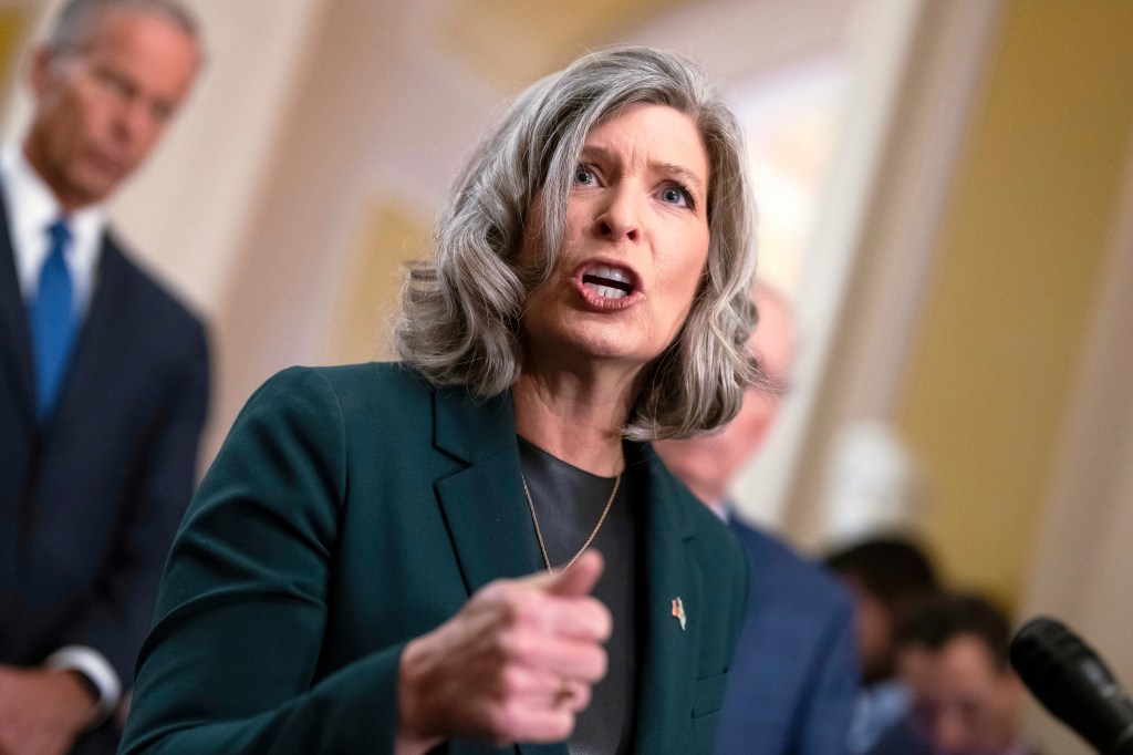 Sen. Joni Ernst speaking to reporters with an open mouth and pointed finger.