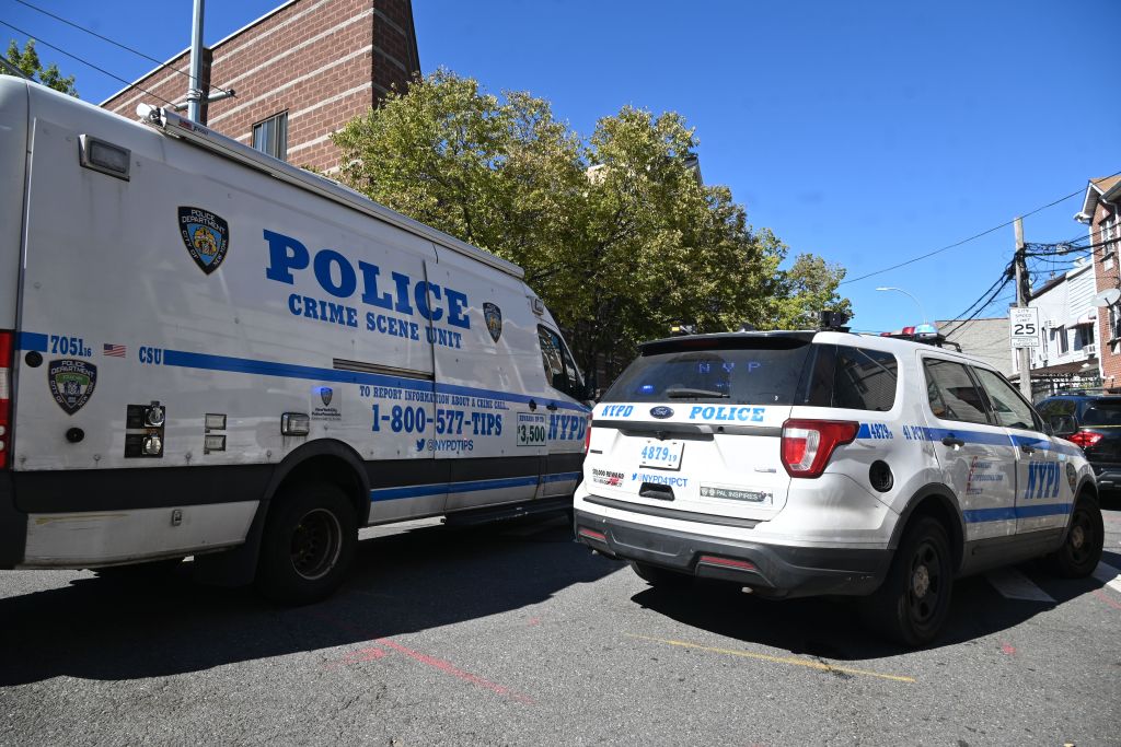 Two NYPD vehicles, a Crime Scene Unit van and a Ford Police SUV, are parked on a street near 952 Rev. James A. Polite Avenue where 46-year-old Amaury Carrion was shot multiple times.