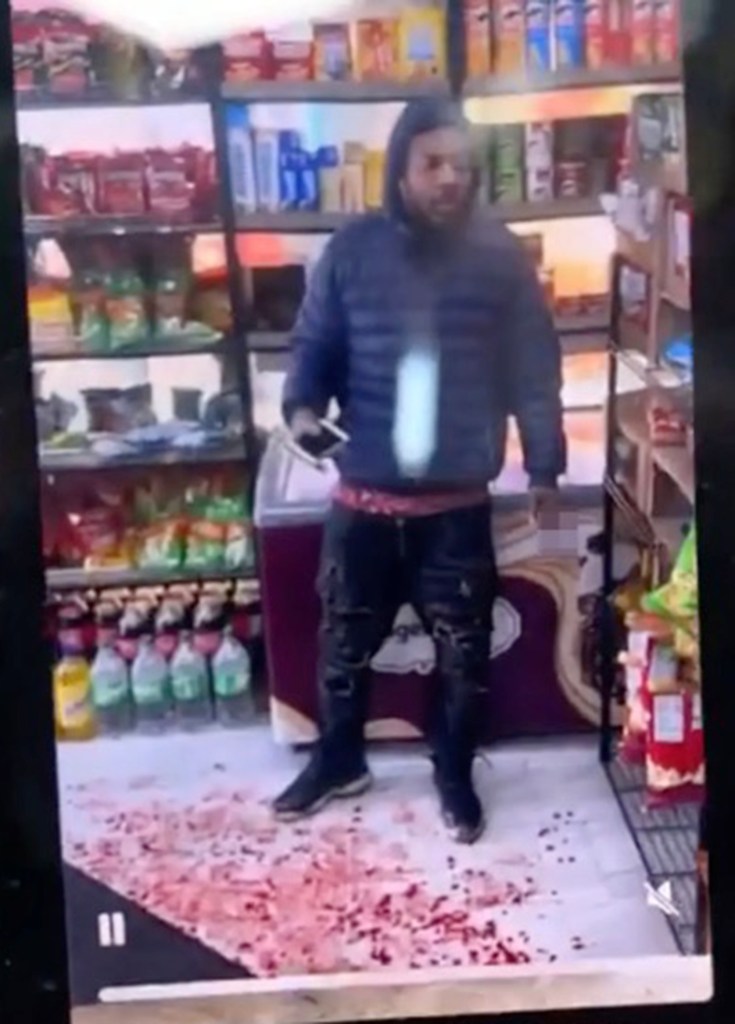 Timothy Bohler in a blue jacket, standing over red spatters on the floor inside a store.